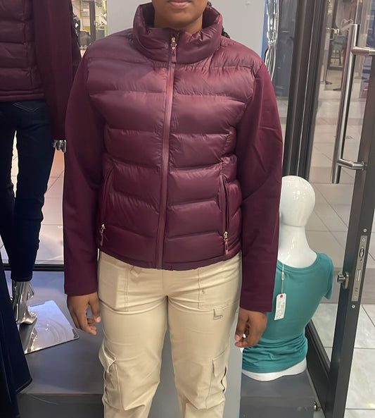 Person wearing a maroon puffer jacket in a store setting